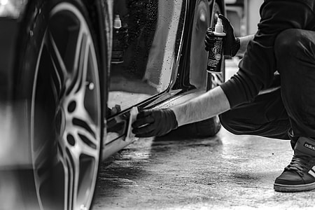 grayscale photo of man cleaning car footboard