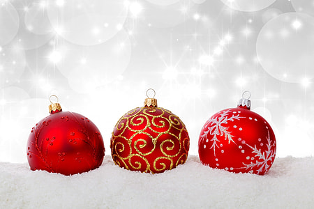 selective color photography of three red glitter baubles on snow surface with lighted background