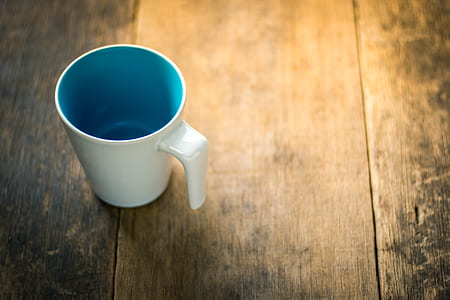 white and blue ceramic mug on brown wooden surface