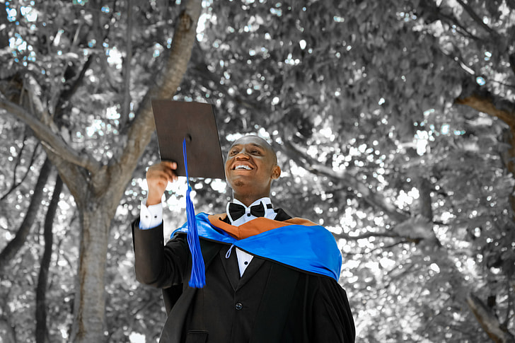 man in black academic dress under trees