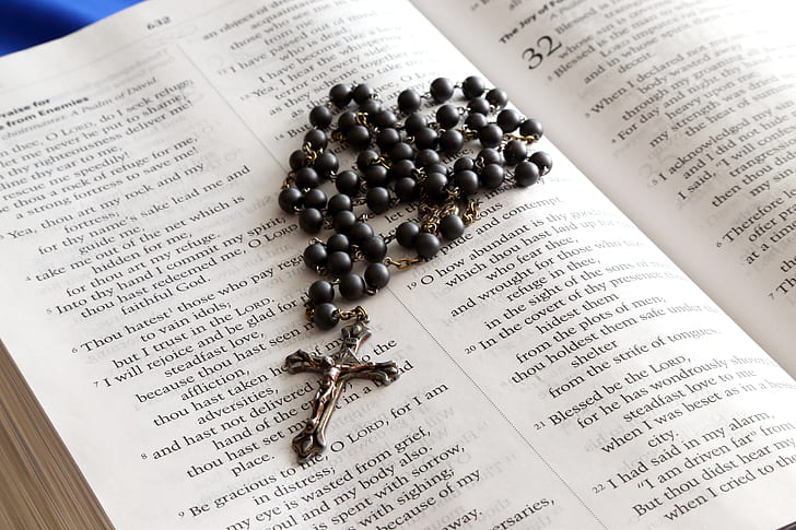 black and silver-colored rosary on bible