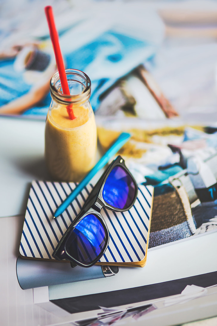 blue wayfarer sunglasses beside clear glass bottle