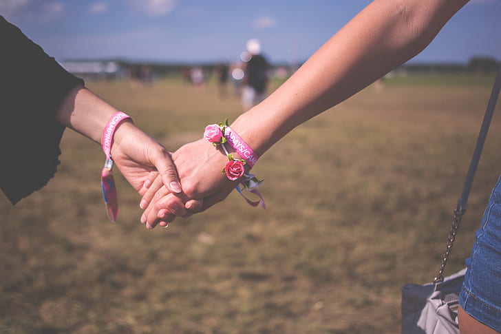 two person holding hands standing on grass field