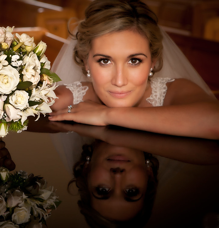 close up photography of bride with hand on black surface with bouquet of white roses