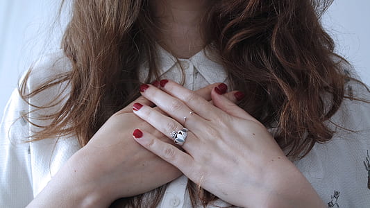 woman wearing two silver-colored ring with clear gemstone and white top