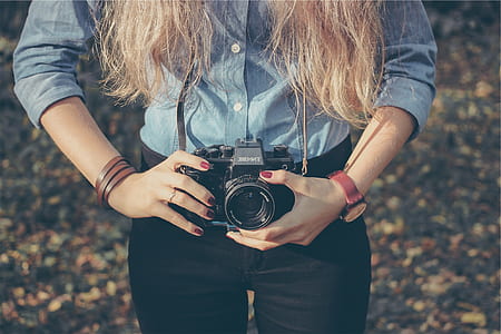 woman holding black DSLR camera during daytime