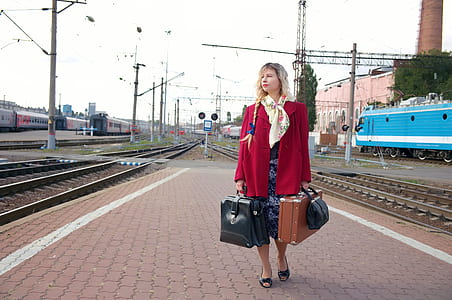 woman holding three assorted bags standing near train rails