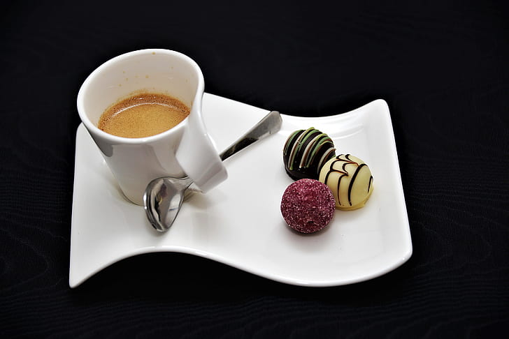 white ceramic teacup with coffee and pastries on top of ceramic dish