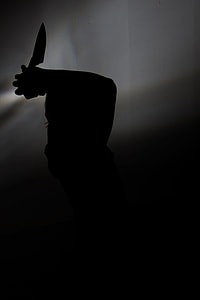 silhouette photo of person holding knife