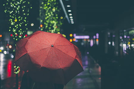 person using red umbrella during nighttime