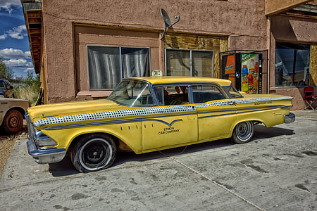 classic yellow sedan taxi cab parked near concrete building