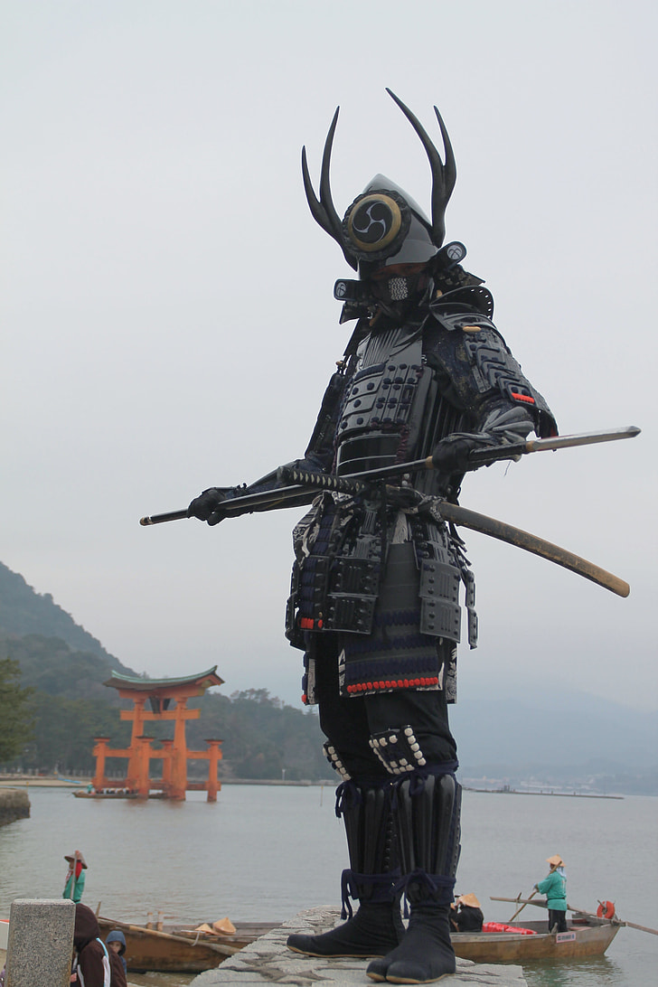 person Yushimitsu costume standing on gray concrete wall