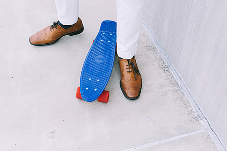 man in brown dressed shoes near the penny board