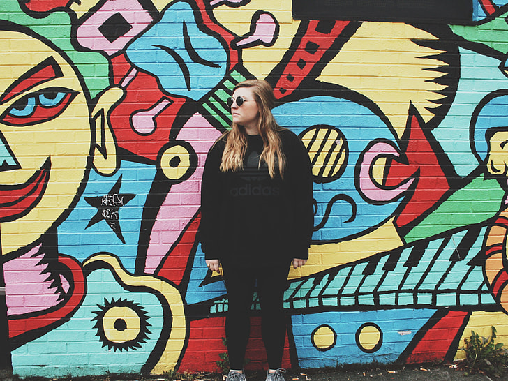 woman wearing black shirt leaning back on graffiti wall