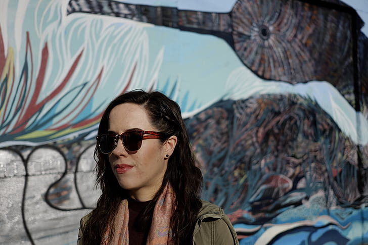 woman wearing black sunglasses beside the mural painting