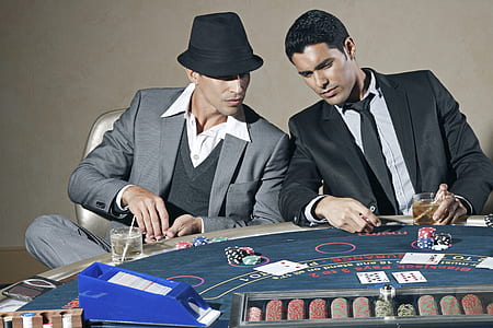 man in black formal suit in front poker table