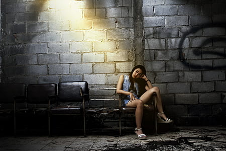 sitting woman on chair beside concrete wall