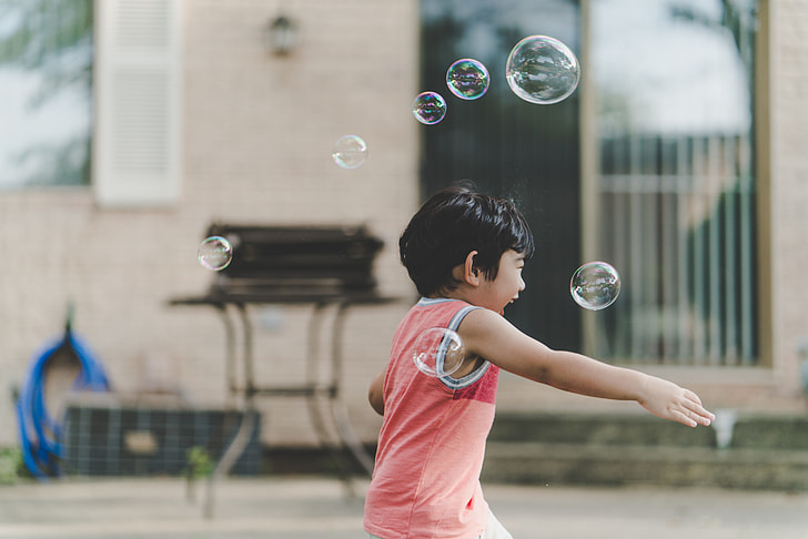 photo of a boy having fun playing with bubbles