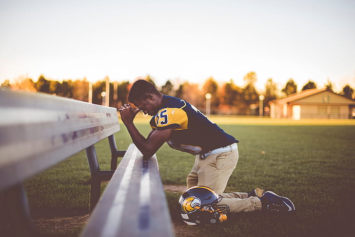 football player praying on bench