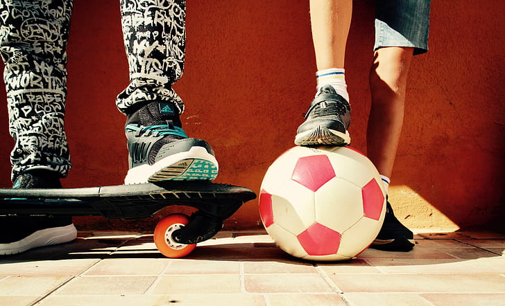 white and red soccer ball beside black skateboard