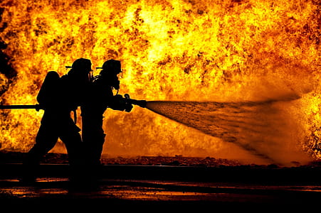 two fireman blowing water using hose on fire
