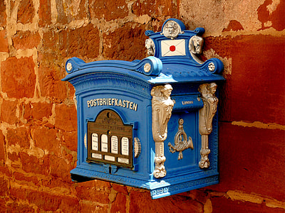 blue and brown steel mailbox attached on red concrete wall