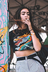 woman standing beside wall smoking