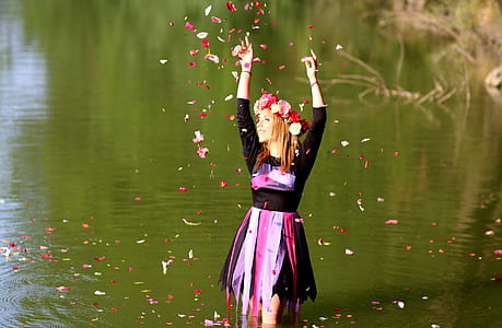 woman throwing petaled flowers in river