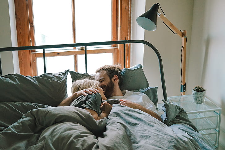 man and human lying on bed and hugging