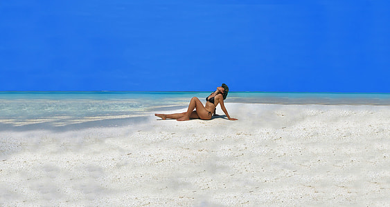 woman wearing bikini doing sun bathing on seashore