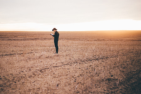 man wearing black suit standing on brown fields