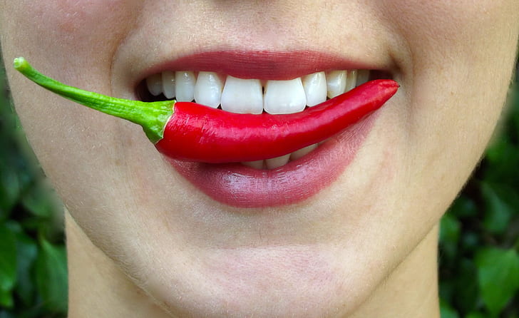 person biting red chili