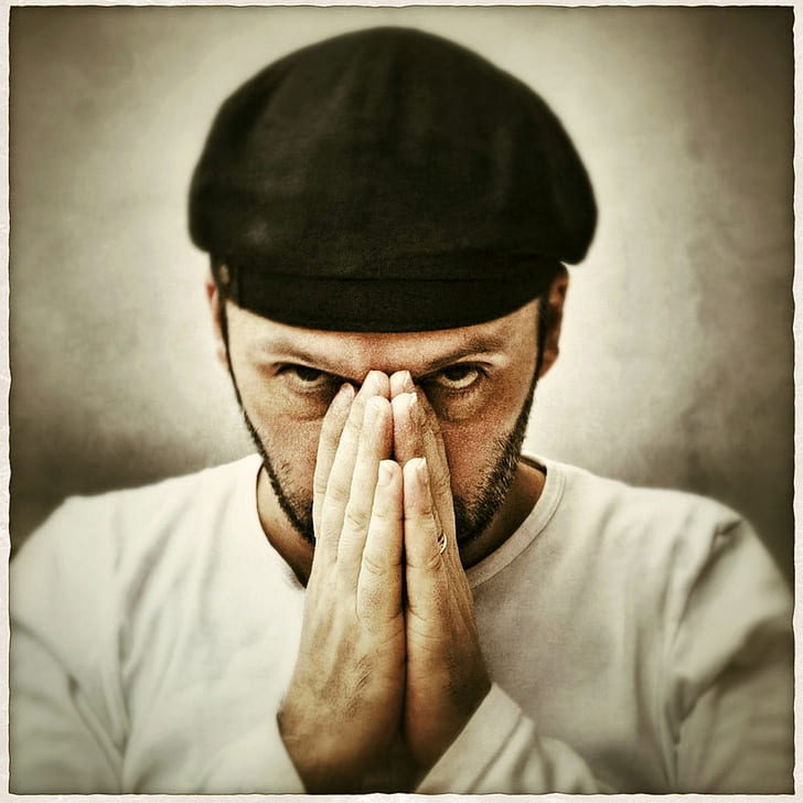 photo of man wearing black cap and white shirt covering his nose