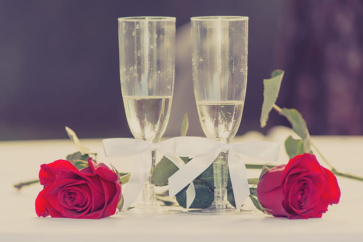 two champagne glasses with two red roses