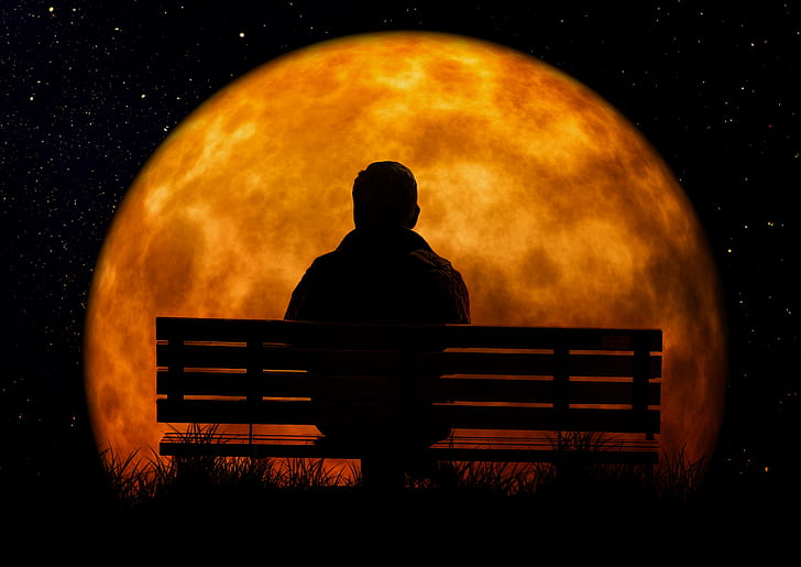 man sitting on bench facing moon