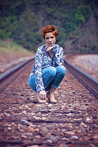 woman in blue long-sleeved top and jeans on train railings