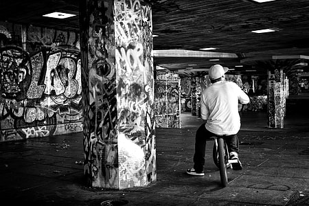 Monochrome shot of a youth sitting oh his BMX bike on the Southbank in London