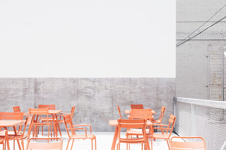 orange metal chairs and tables on rooftop during daytime
