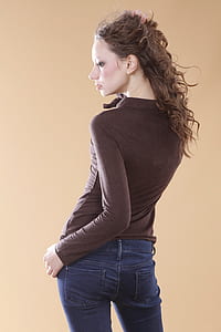 photograph of woman in brown sweat shirt and blue denim jeans