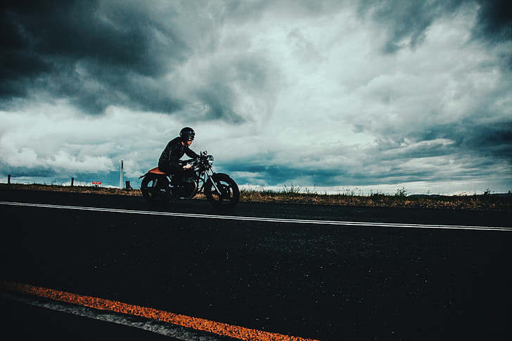 Moody shot of a man on the road riding a motorbike