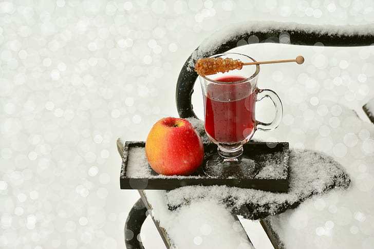 clear glass footed mug and red apple on black wooden ice covered tray