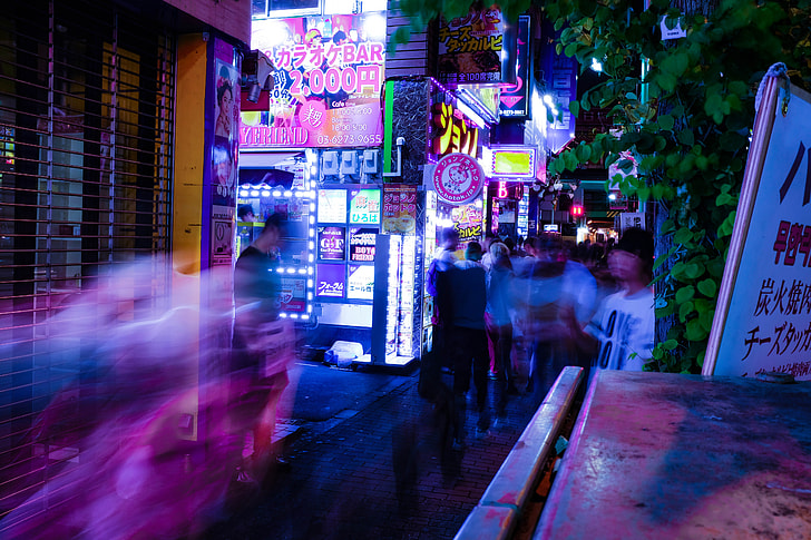people in clothing on motion on pathway between buildings during nighttime