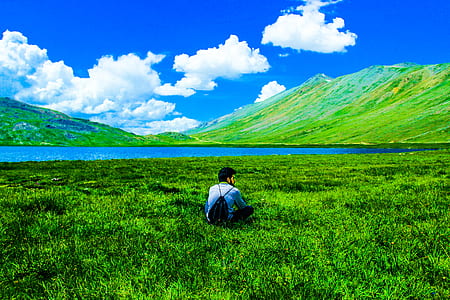 Boy Sitting on Green Grass Field