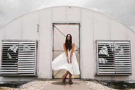 woman wearing white sleeveless dress standing in front of white painted door