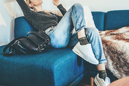 woman wearing black blue denim jeans sitting on the sofa