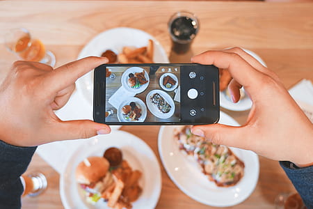 person holding smartphone taking picture to the food