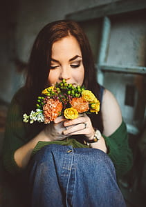 closeup photography of woman smelling bouquet of flowers