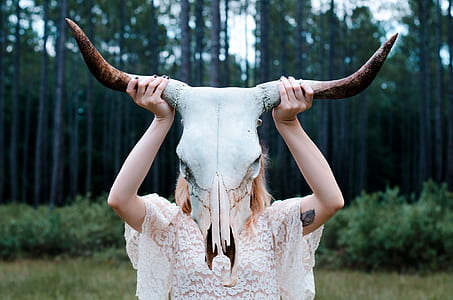 girl holding horned animal skull during daytime