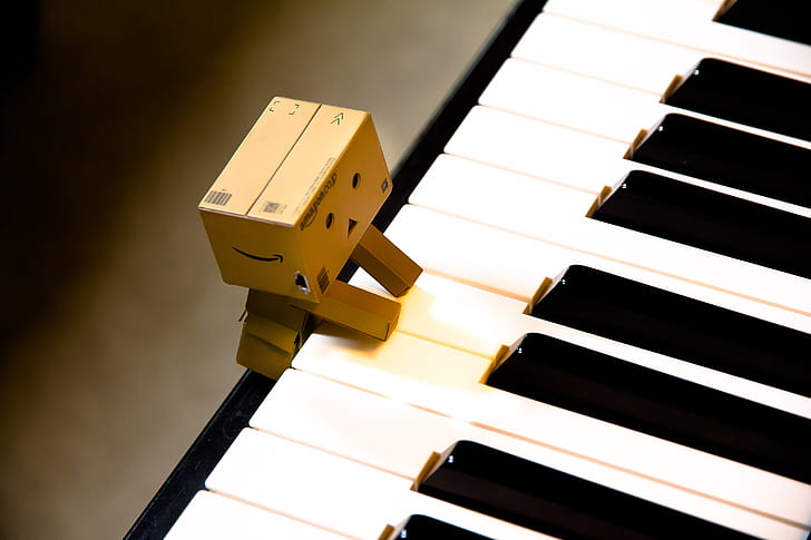brown cardboard character on top of white piano
