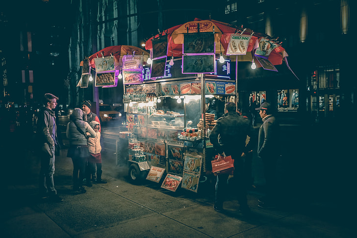 photography of people standing near food stand during night time